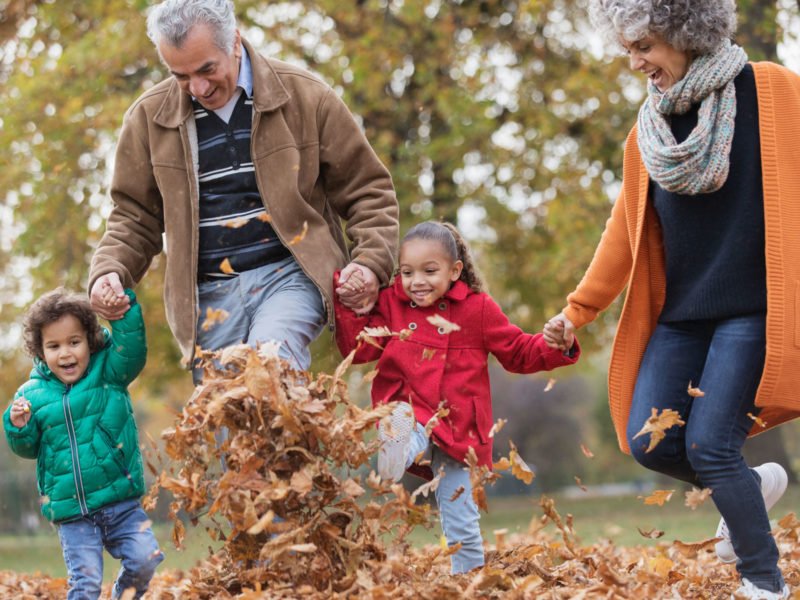 Grandparents and children playing in autumn leaves